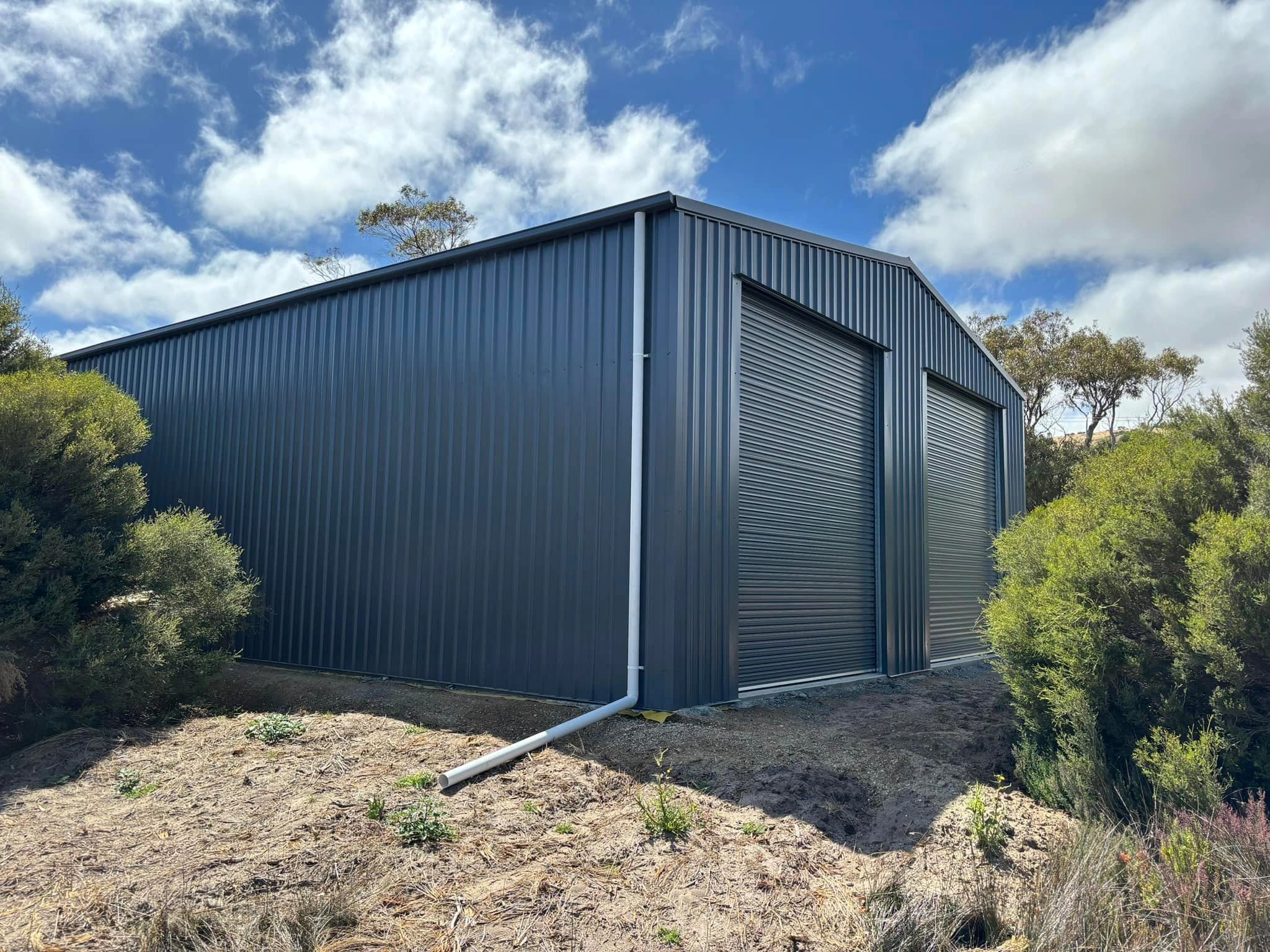 Dark corrugated steel industrial shed with roller doors